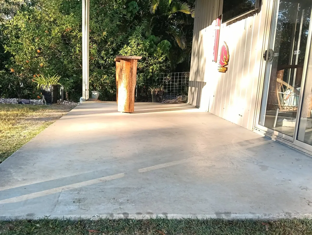 Plain concrete alfresco slab beside a shed before coating
